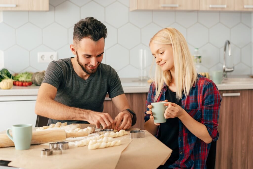Young couple girl and guy in the kitchen are preparing dough